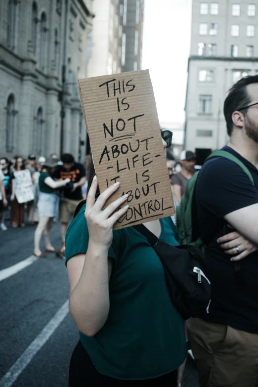 a protester is holding a sign reading this is not about life but control