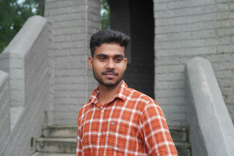 a young man with an orange checkered shirt on