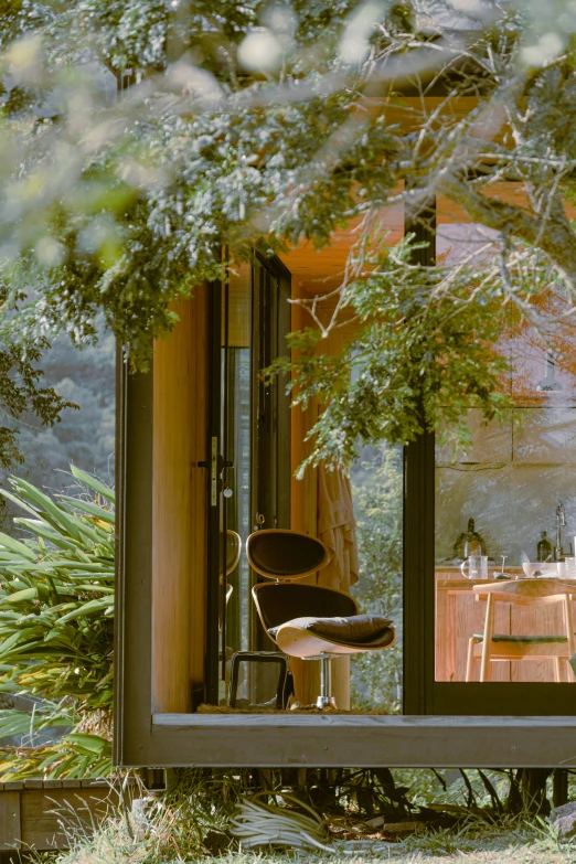 a view into the outside kitchen and dining room from a bench in front of some trees