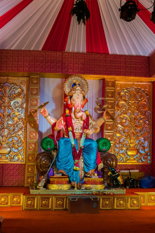 a statue on top of a wooden table in a red and gold colored area