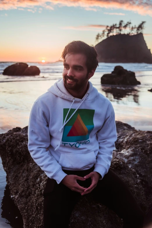 the man sits on the rocks, with the sun in the background