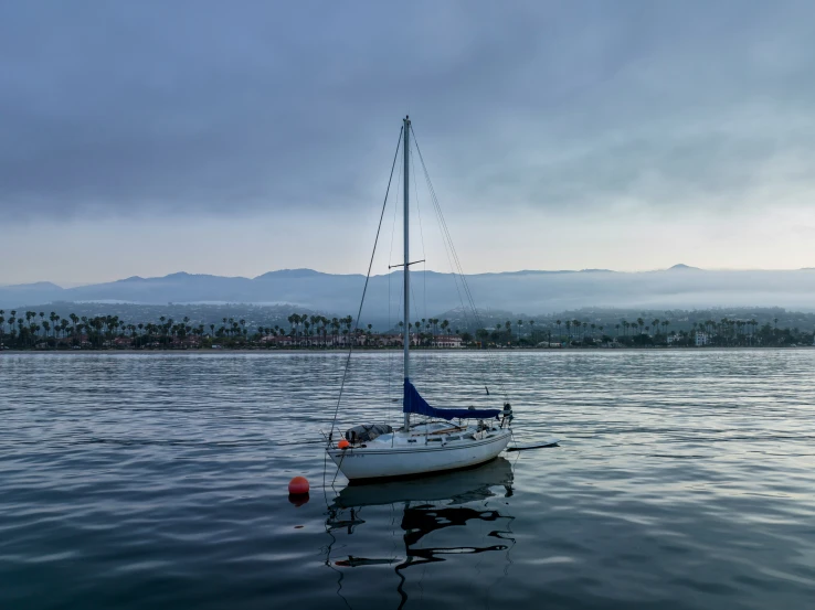 there is a small white sail boat in the water