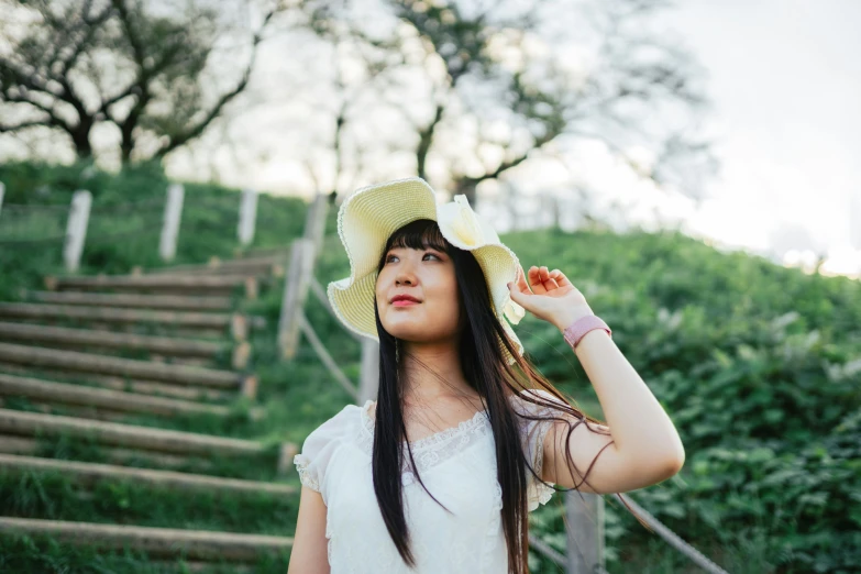 woman wearing a sun hat walking up stairs to a hill