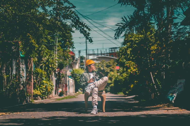 a man sitting on top of a chair by a tree