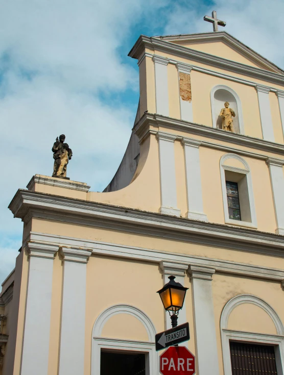 a yellow church has a statue on the top