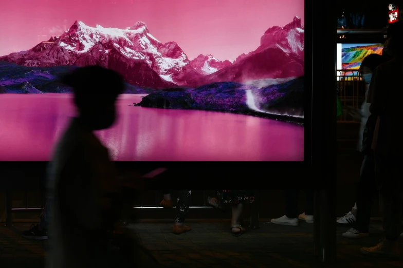 a man walking in front of a tv screen with purple mountains on it