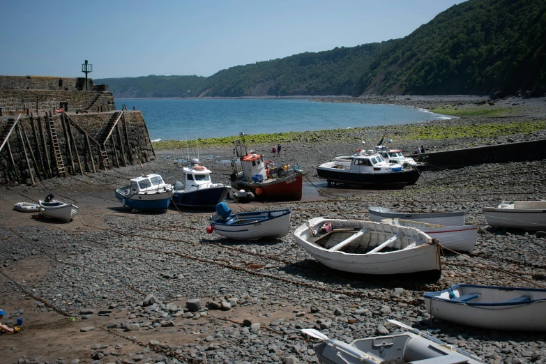 several small boats are parked on a pebbly beach