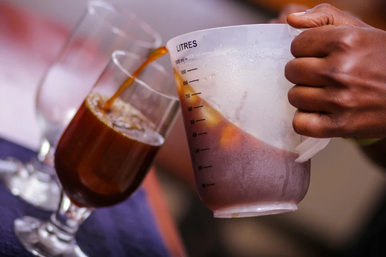 two people holding drinks and a measuring cup