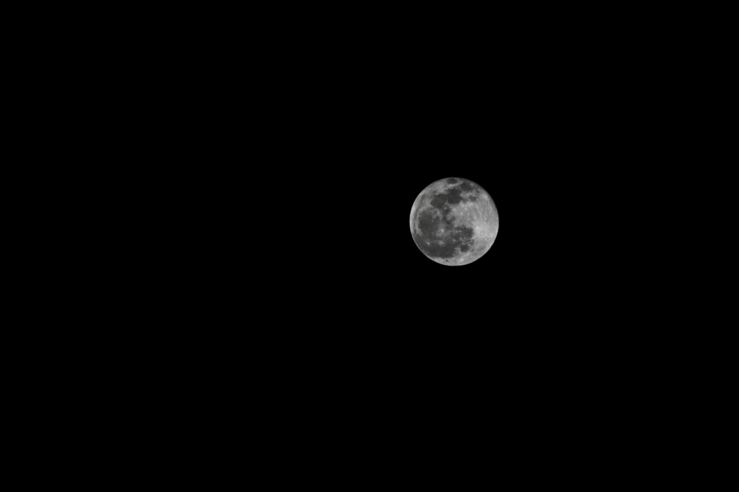 the moon lit up against black sky at night