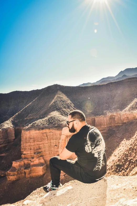 man looking out over the desert and mountains with his hands in his pockets