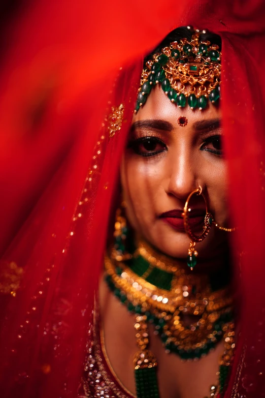 a woman dressed in a red veil and jewelry