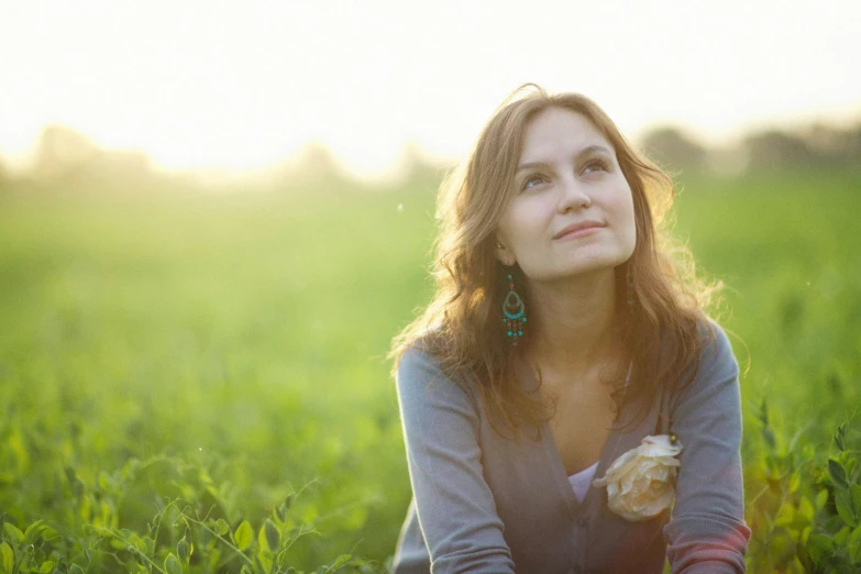 an attractive woman holding a donut sitting in the grass