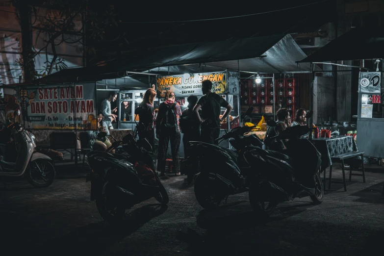 a group of people on motor bikes parked in a lot