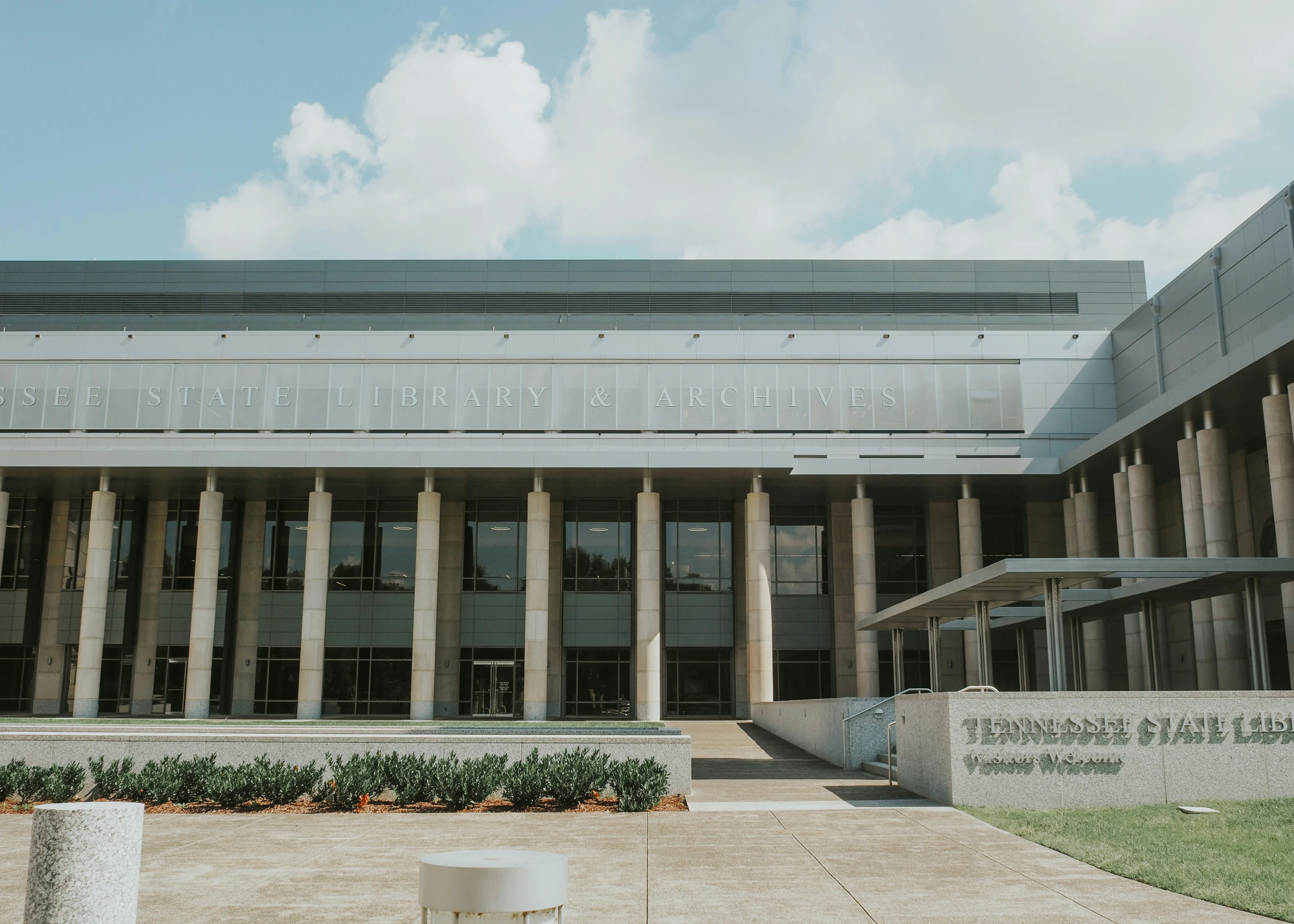 an open area with a tall building, pillars, and flags