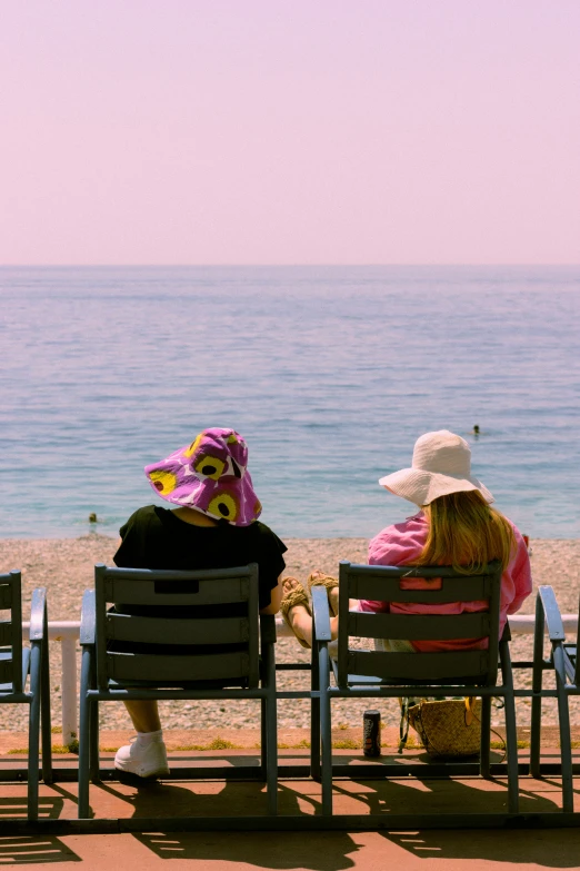 two women sitting on beach chairs next to the ocean