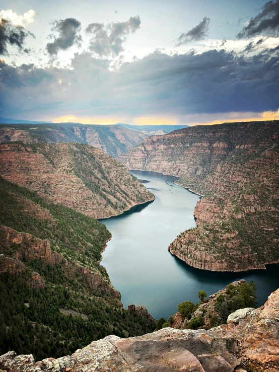 a large lake sits below dark clouds near a mountain