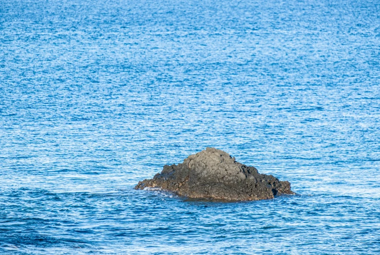 a small rock in the middle of some water