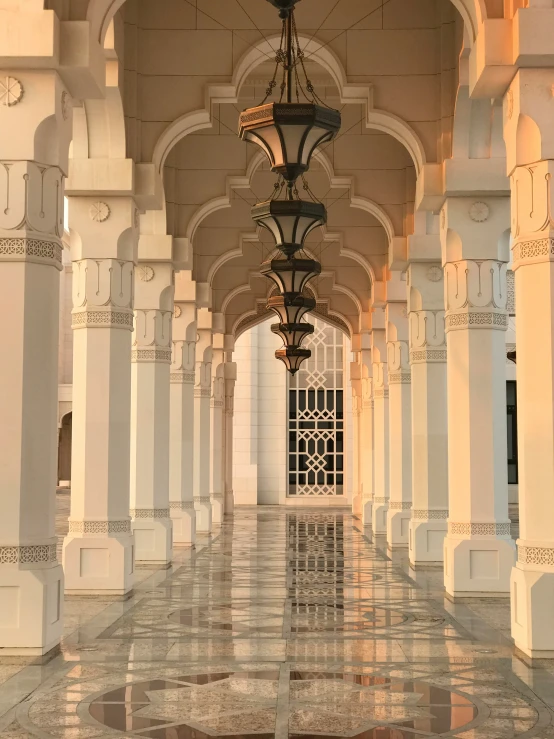 an elegant hallway with several pillars and hanging lights