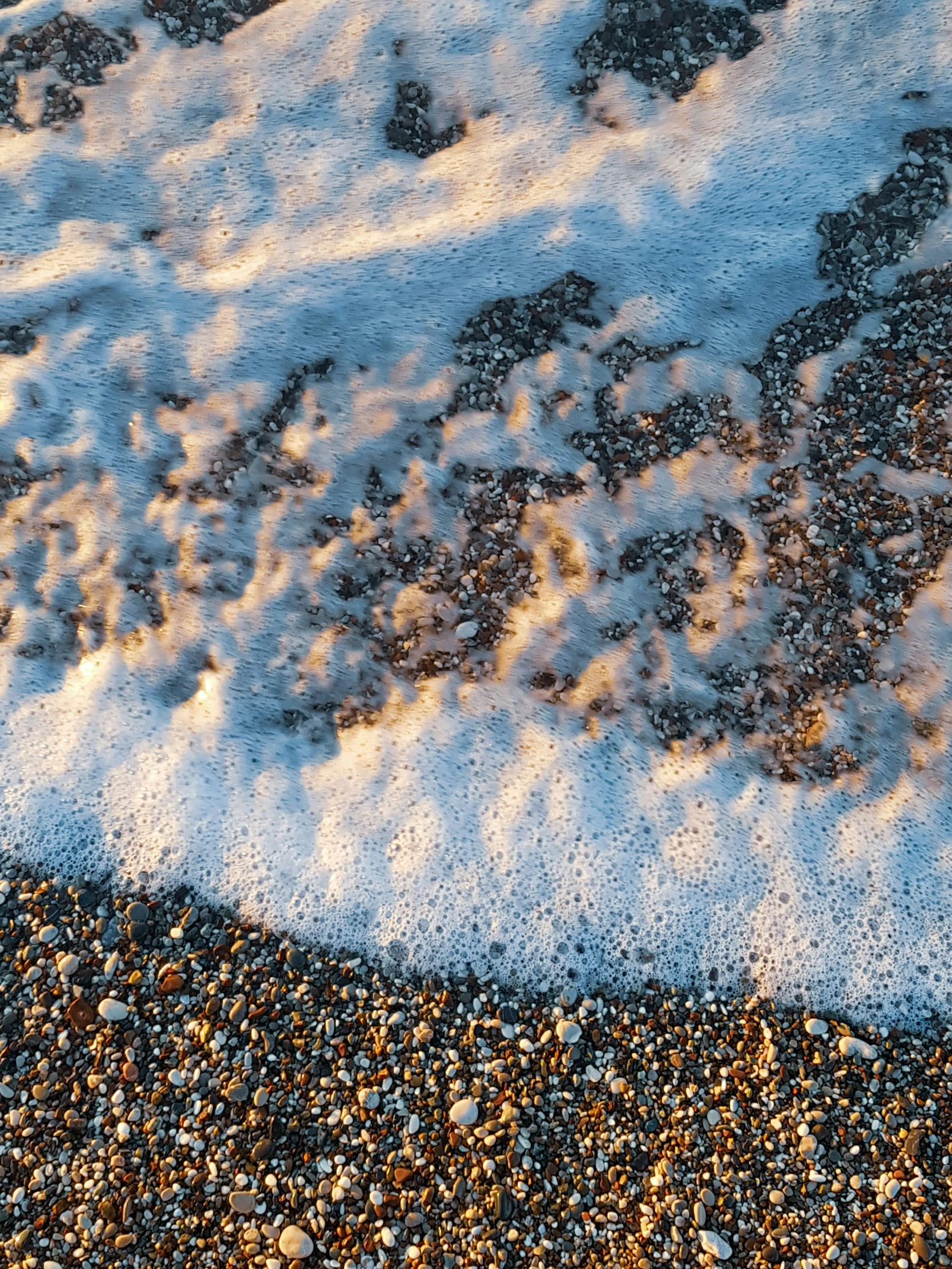 the sand, water and rocks under a wave