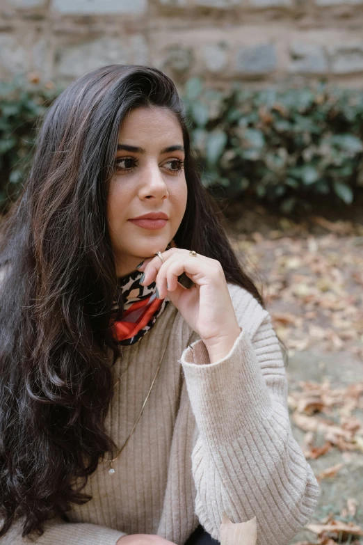 a  with long black hair is sitting in front of a brick wall