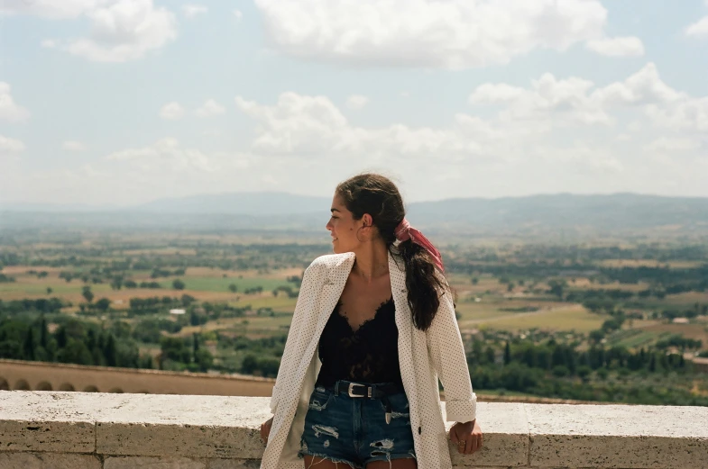 a woman is overlooking the landscape on top of the hill