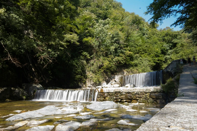 a waterfall that is next to some trees and rocks