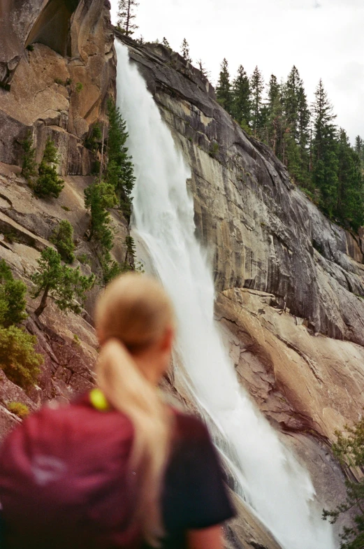 two people are observing a waterfall from the ground