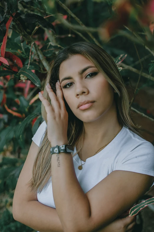 a young woman leaning on a bush with her hands near her face