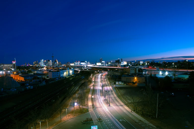 traffic in an intersection at night with city lights in the background