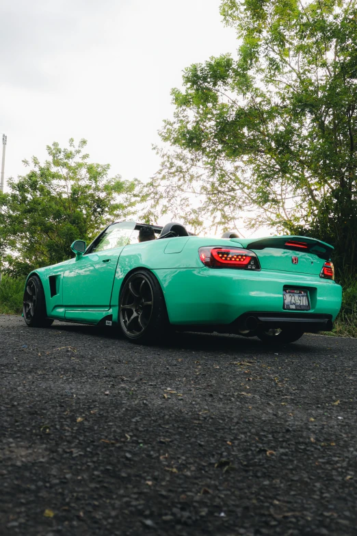 an aqua colored sports car parked on the side of a road