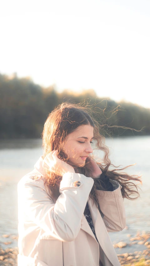 the woman in white jacket is walking beside a river