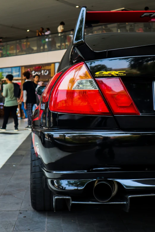 the rear end of a black sedan parked on a sidewalk