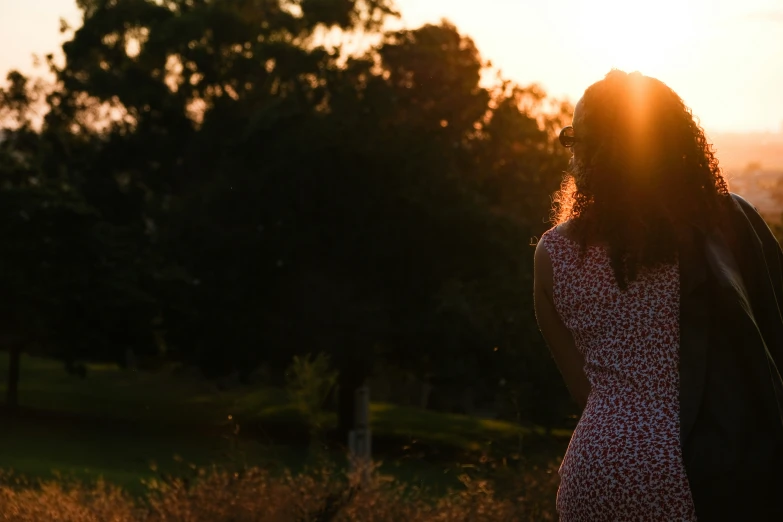 a woman stands in a field looking at the sun