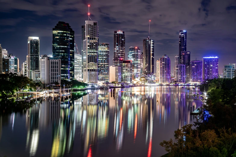 city skylines shine brightly at night along a body of water