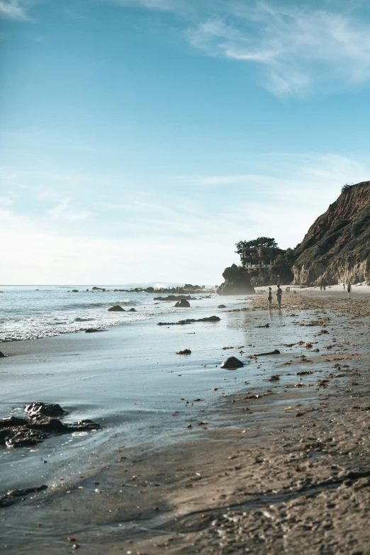 the people are walking on the beach near the water