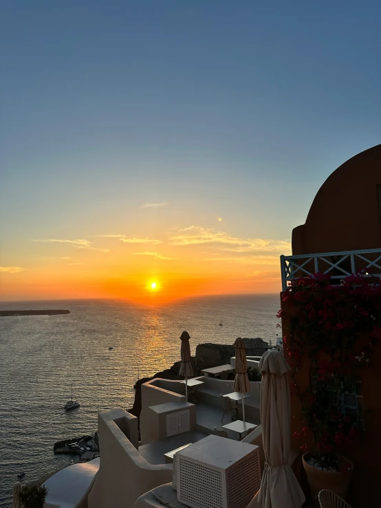 an ocean with chairs under the setting sun