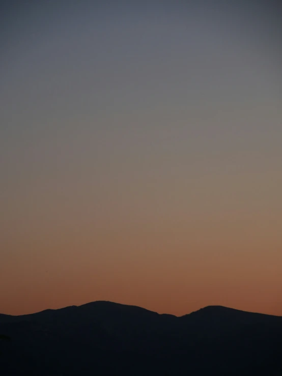 a plane in the sky flying above some hills