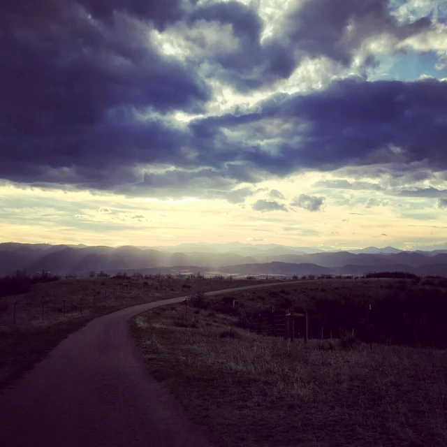 a winding path winds through a field in the distance is mountain range