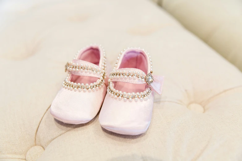 small pink baby shoes sitting on top of a white blanket
