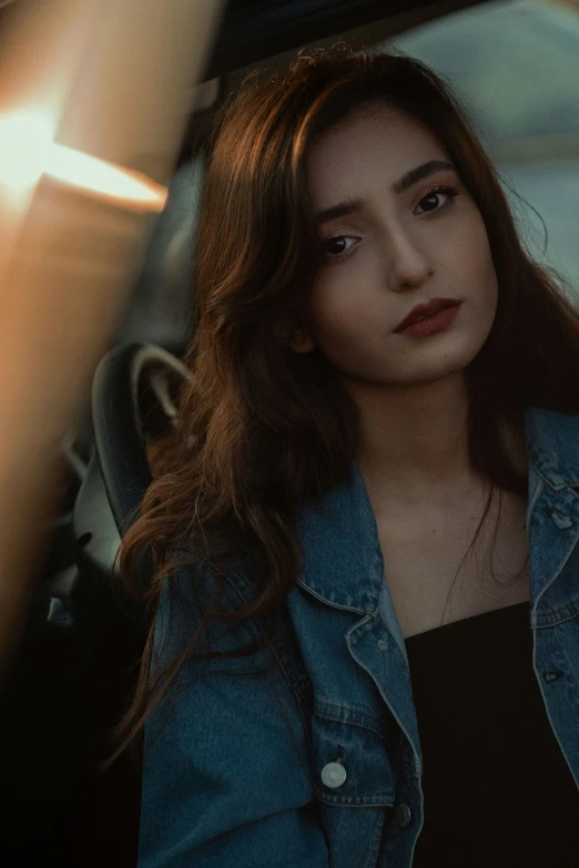 a woman sitting in a car holding her hand up to her face