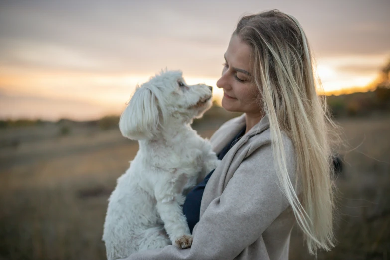 woman in a gray sweater holding white dog