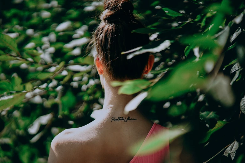 woman in a forest looking through some leaves