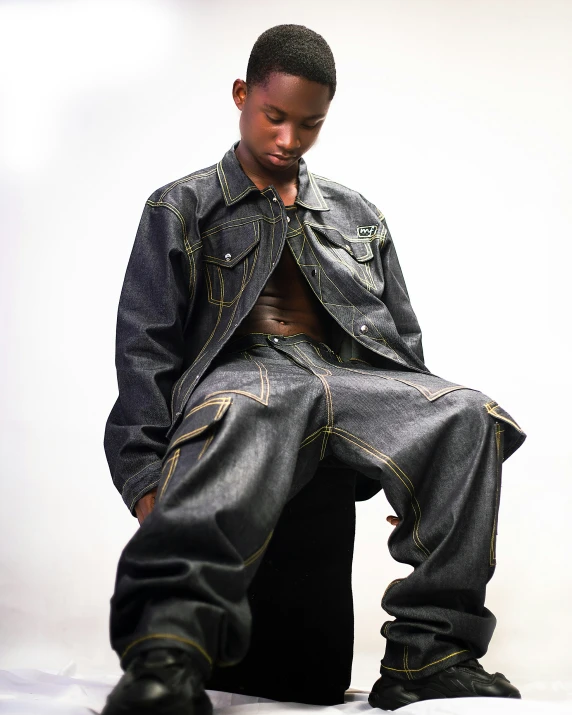 a man sitting on top of a white bed wearing black jeans