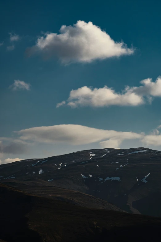 a group of clouds rolling through the air over hills