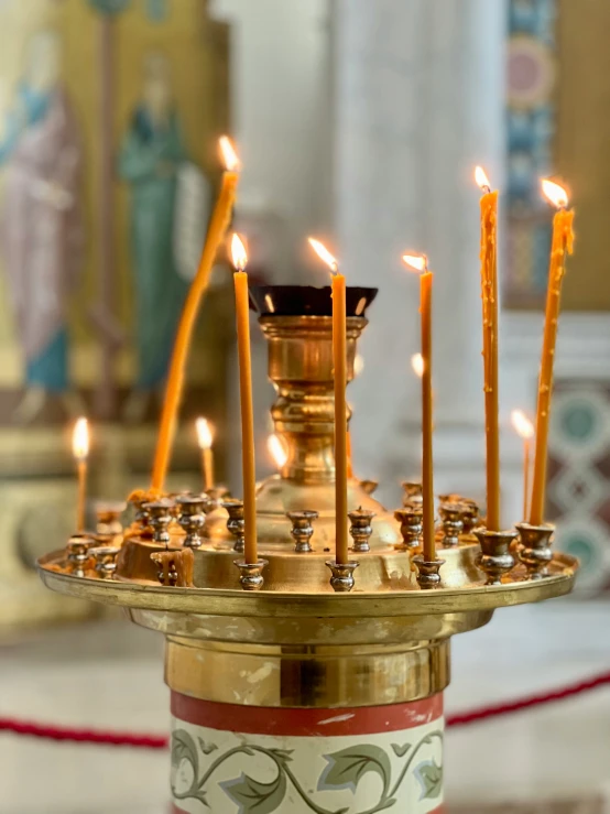 small candles lit and on a tray in front of a statue