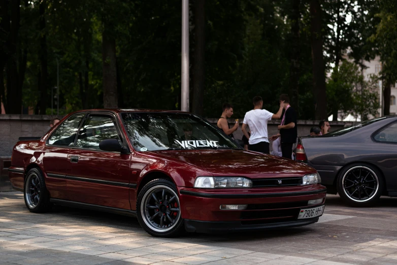 some people gathered around a maroon car