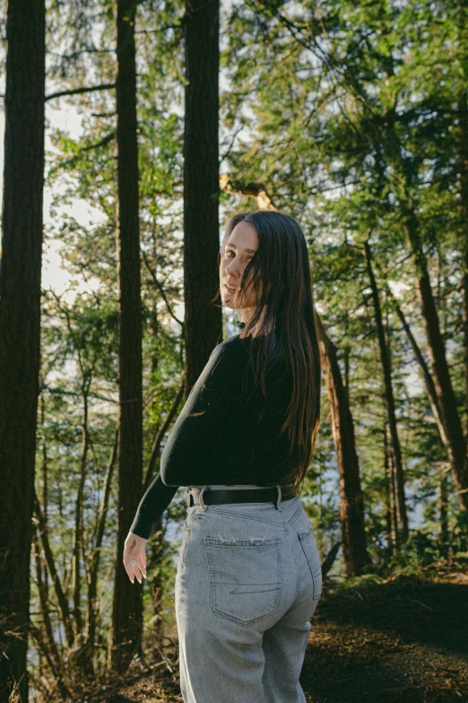 a girl standing next to a forest and trees