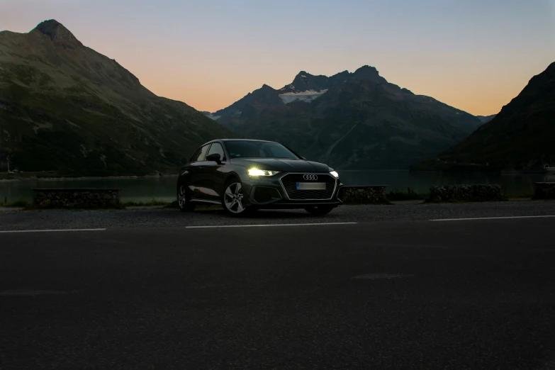 a black car parked in front of mountains