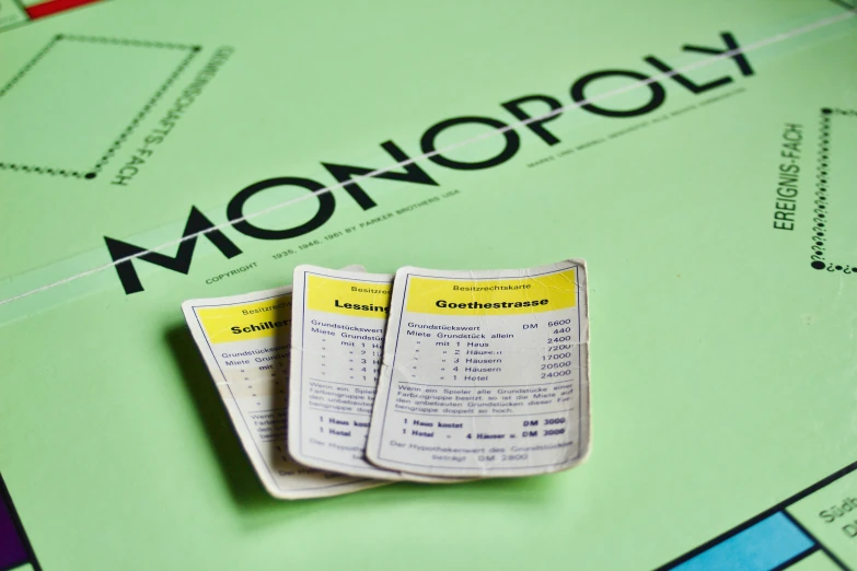 two yellow paper flyers sitting on top of an monopoly board