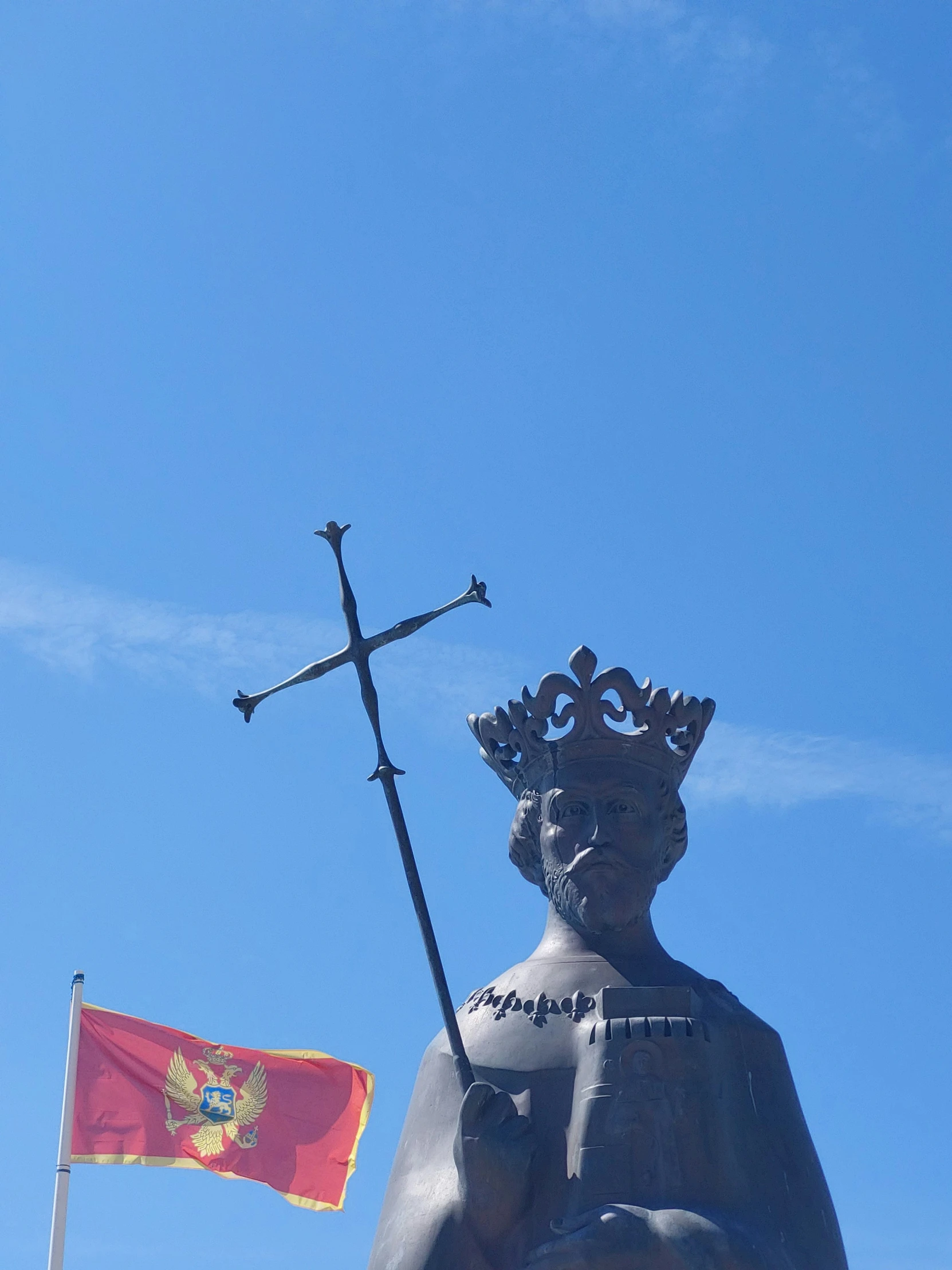 a statue with a cross on it and two flags behind